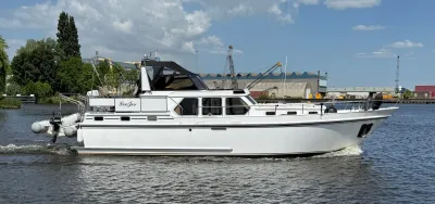 wit motorjacht varend op water met bijboot