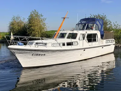 wit motorjacht op rustig water bij oever