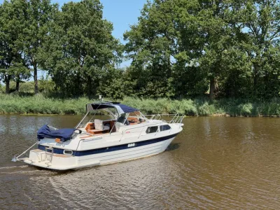 motorjacht op rivier bij boomrijke oever