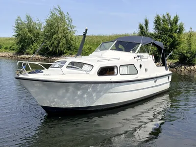 witte motorboot op stil water bij oever