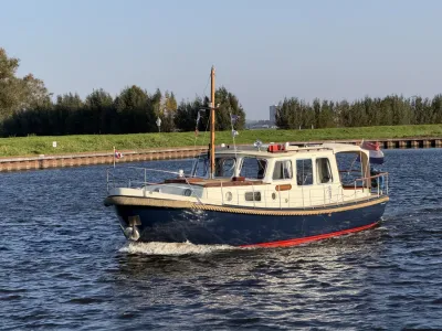 varend motorjacht op water bij oever