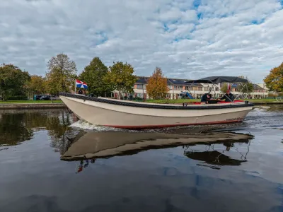 witte sloep op water met huizen op de achtergrond